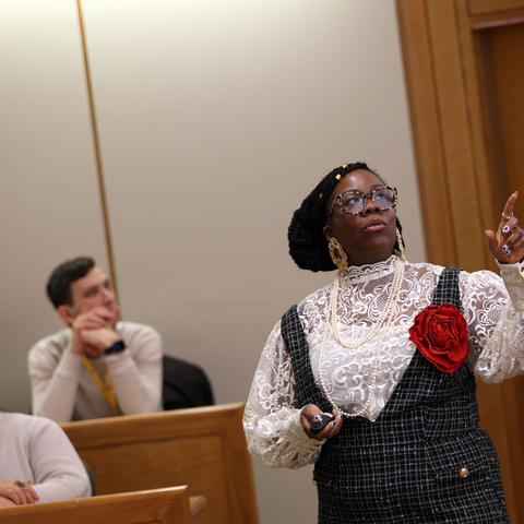 A workshop presenter who is pointing and facilitating in a room with participants.